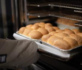 Pans of golden dinner rolls coming out of the oven